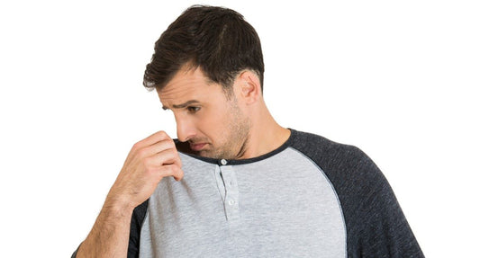 man sniffing clothes from sweaterwomen rubbing deodorant in underarms